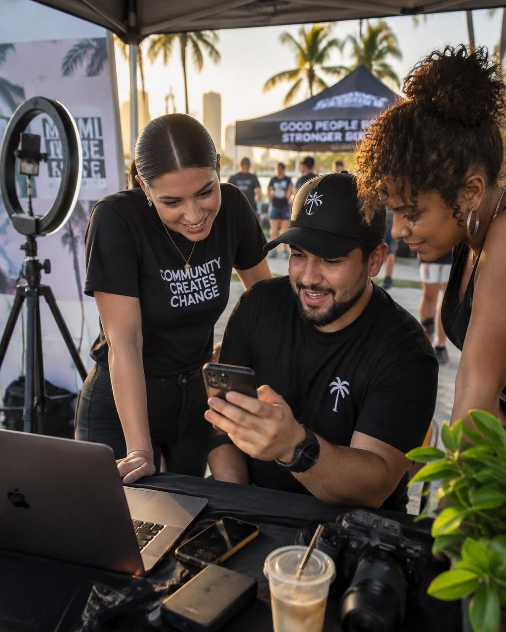 Content crew reviewing footage at an outdoor Miami community event booth